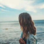 Νεαρό κορίτσι που ατενίζει την θάλασσα σαν να κοιτάζει το παρελθόν της