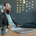 Άνδρας χαλαρώνει στο γραφείο του ακούγοντας μουσική και βιώνει ψυχική γαλήνη μέσα στο χάος της καθημερινότητας